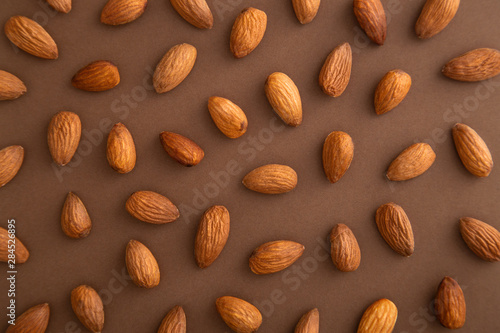 Almonds pattern on a brown background viewed from above. Nuts creative layout. Top view