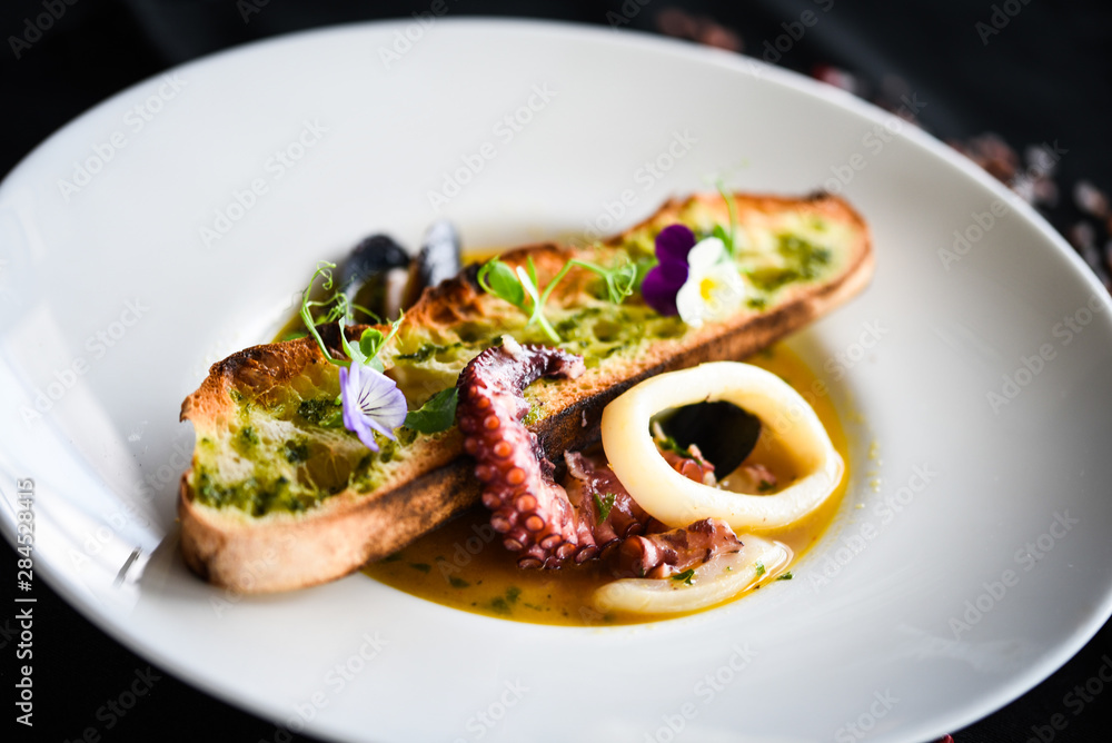 tasty seafood soup with fresh vegetables - shrimps, shells, octopus and crispy home made bread