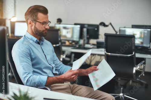 Businessman at work. Young andsuccessfulbearded man working on computer while working in modern office