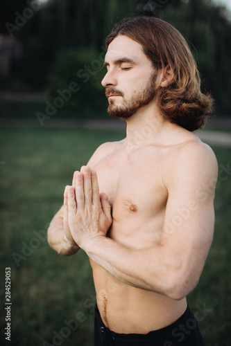 Yoga at park. Bearded man doing yoga in the green park. Concept of a healthy lifestyle. photo