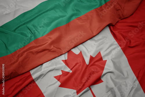 waving colorful flag of canada and national flag of bulgaria.