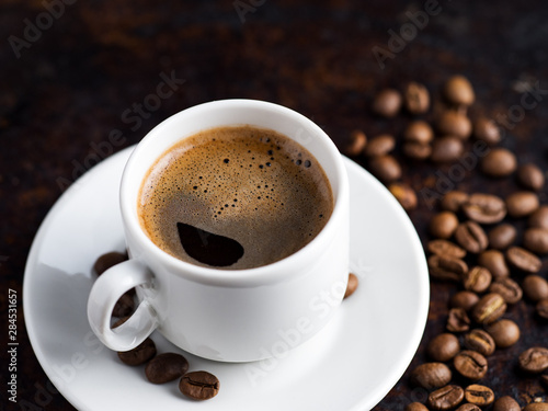 White espresso coffee Cup and coffee beans on rusty dark background
