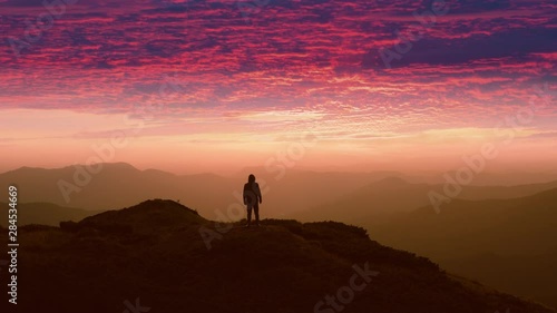 The man standing on a mountain top against the beautiful sunset