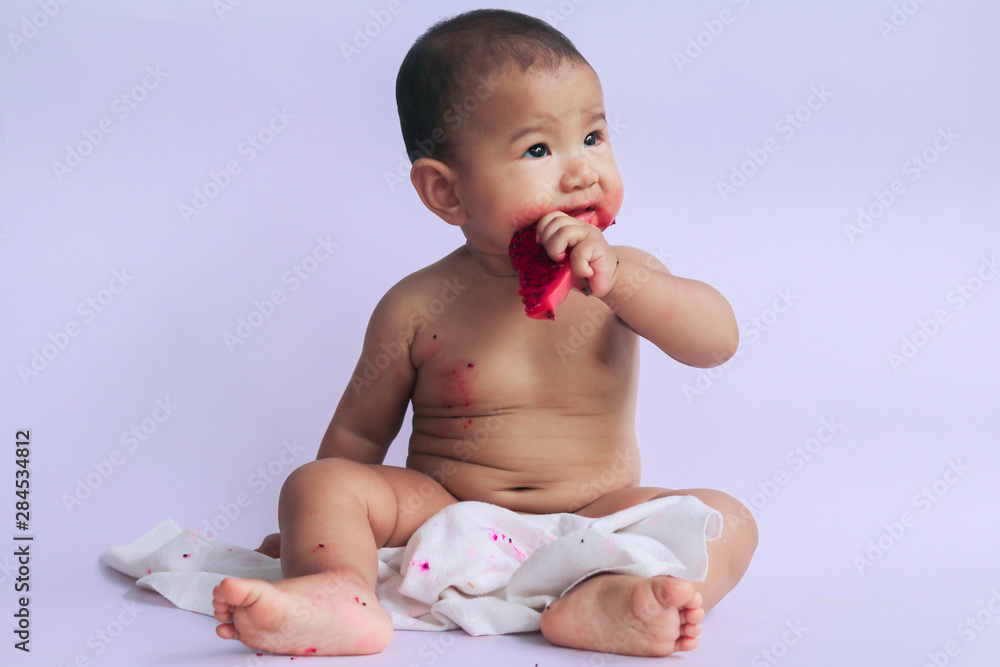 asian cute baby girl eating red dragon fruit. newborn baby on white background asian cute baby girl eating red dragon fruit. newborn baby on white background