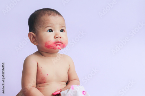 asian cute baby girl eating red dragon fruit. newborn baby on white background