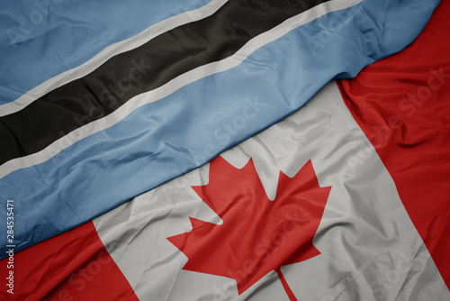 waving colorful flag of canada and national flag of botswana.