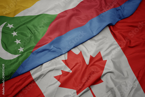 waving colorful flag of canada and national flag of comoros.