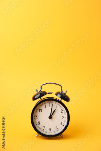 black alarm clock on a yellow background