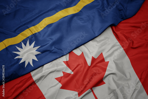 waving colorful flag of canada and national flag of Nauru.