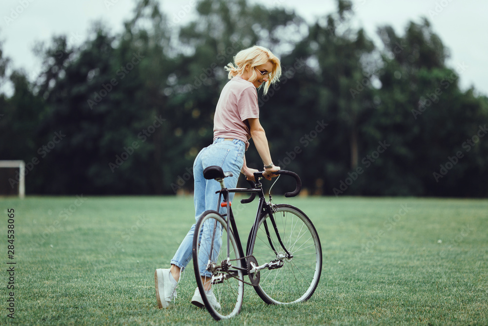 Pretty woman using cycling on the street,outdoor fashion portrait,hipster style ,sunglasses, sneakers,outdoor woman portrait on bike cycle,happy face,close up.spring, sunglasses fashion,cute,emotional
