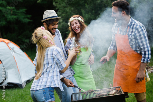 Group of happy friends having barbecue party in forest