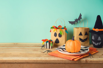 Halloween holiday table setting with glitter pumpkin, party gift paper bag decor and candy