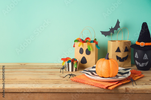 Halloween holiday table setting with glitter pumpkin, party gift paper bag decor and candy photo