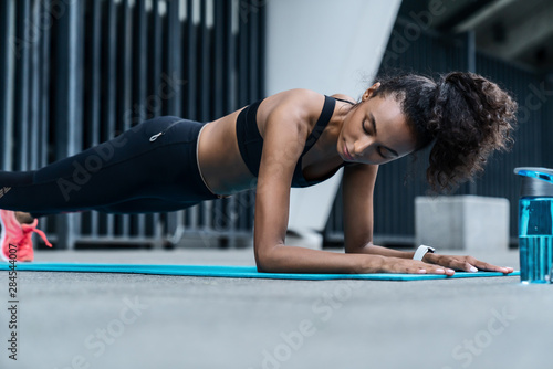Young female girl in sportswear working out on fitness mat