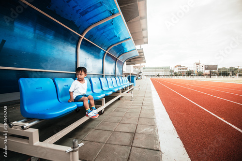 baby boy sitting on chair in stadium and track