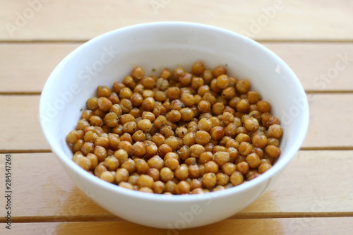 Bowl of roasted crispy chickpeas on wooden table. Selective focus.
