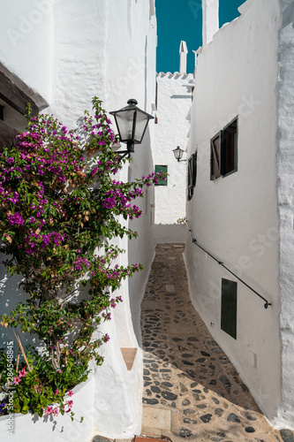 Narrow street among whitewashed houses in the traditional fishing village of Binibeca on the mediterranean coast of Menorca  Spain. Town with Ibiza style.