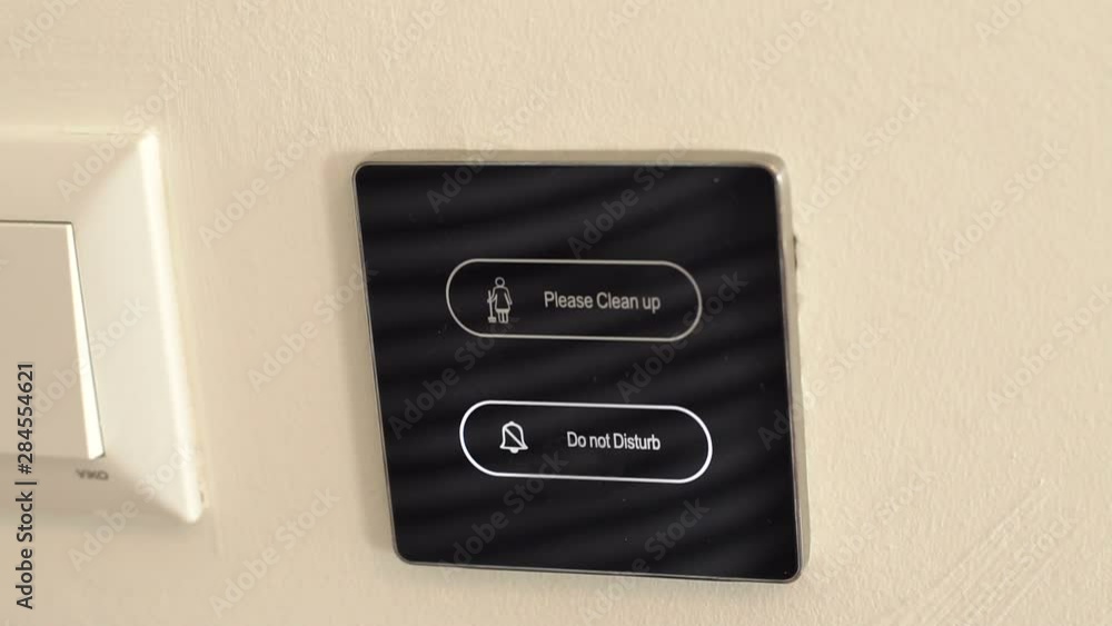 Close-up of the woman presses the button with the do not disturb sign on the door lock in the hotel. Finger on electronic doorbell with display box showing Do not disturb. Close-up of the woman presses the button with the do not disturb sign on the door lock in the hotel. Finger on electronic doorbell with display box showing Do not disturb.