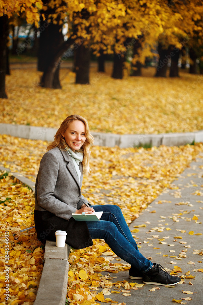 Woman sitting on a curb writing something in her notebook