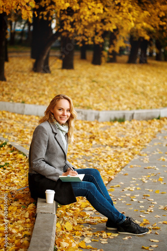 Obraz na płótnie Woman sitting on a curb writing something in her notebook w salonie