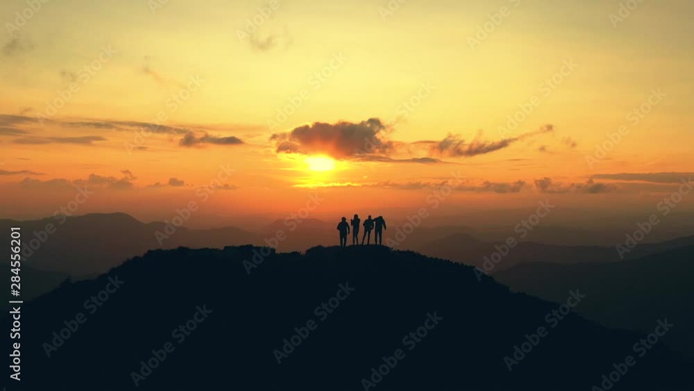 The four people dancing on a mountain against the picturesque sunrise The four people dancing on a mountain against the picturesque sunrise
