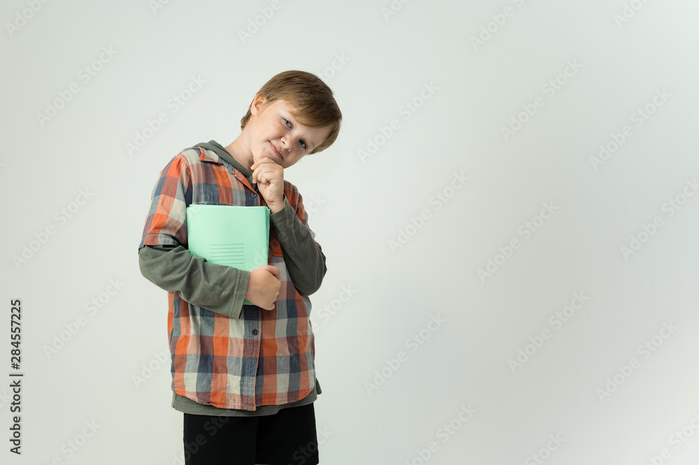 Photo is a waist-high portrait of a funny cheerful cute happy school-age boy with school notebooks in his hands. Rejoices, smiles on a white background. Shows hands. Photo is a waist-high portrait of a funny cheerful cute happy school-age boy with school notebooks in his hands. Rejoices, smiles on a white background. Shows hands.