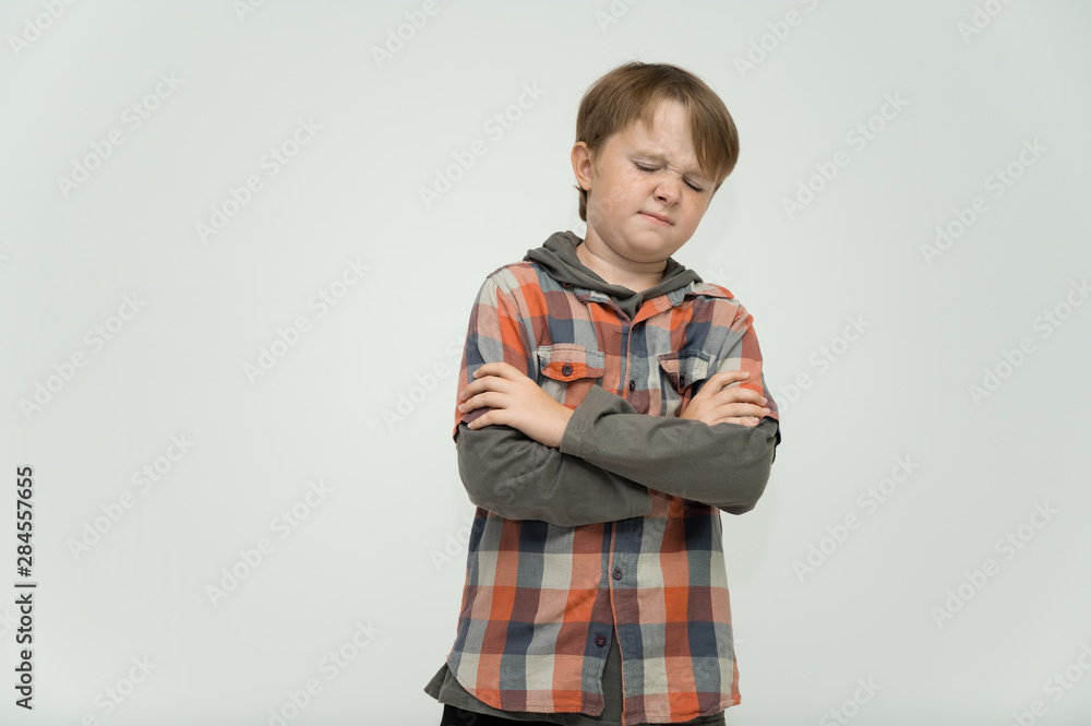 Photo portrait waist-high of a fun cheerful cute happy school-age boy. Rejoices, smiles on a white background. Shows hands.