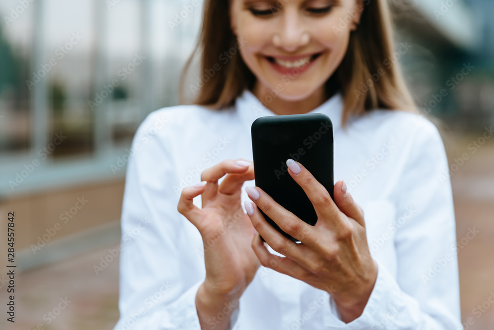 Cropped view of businesswoman using smartphone. Successful female entrepreneur checking email on smartphone. Female texting message. Office building Background. Technology internet and happy people Cropped view of businesswoman using smartphone. Successful female entrepreneur checking email on smartphone. Female texting message. Office building Background. Technology internet and happy people