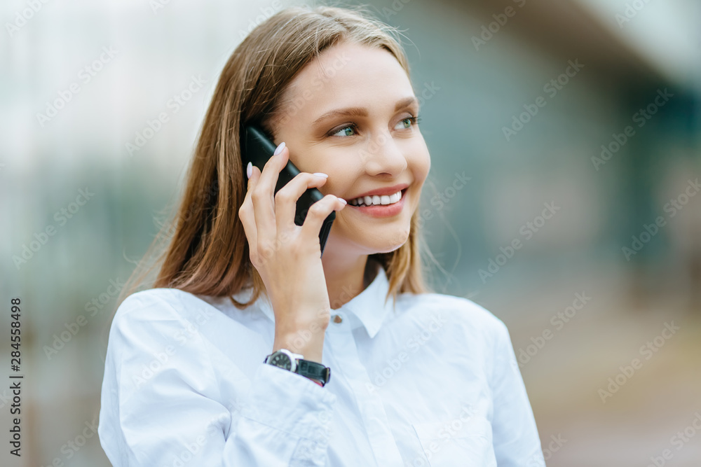 Young famale calling on a smartphone. Attractive businesswoman talking by phone. Office building Background. Technology internet and happy people concept. Young famale calling on a smartphone. Attractive businesswoman talking by phone. Office building Background. Technology internet and happy people concept.