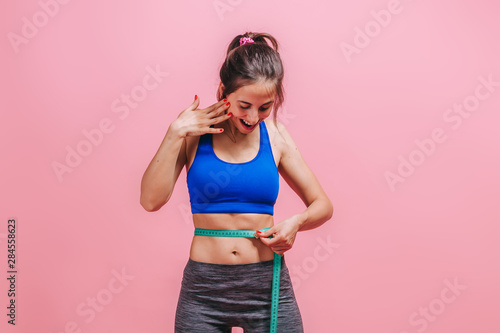girl measures a waist on a pink background © Smeilov