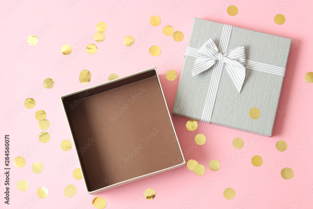 open gift box and confetti on a colored background top view.
