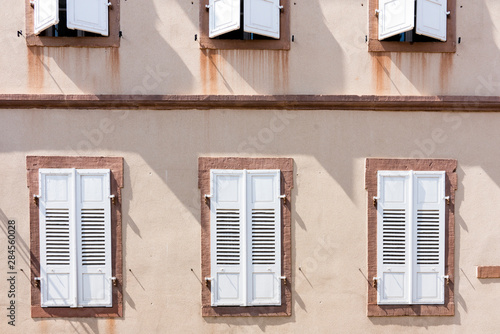 pink oncrete wall with white shutters. Wissembourg, France photo