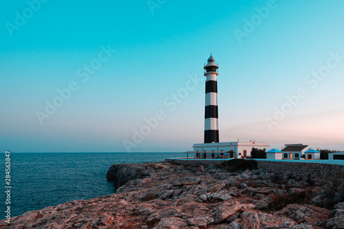 Blue hour view of the Cap Artrutx Lighthouse or Artrutx Lighthouse  an active 19th century lighthouse located on the low-lying headland of the same name on the Spanish island of Menorca. Orange and