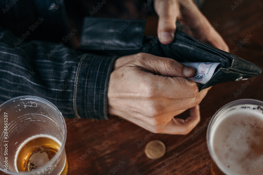 Hands get money from the wallet. Near glass of beer Hands get money from the wallet. Near glass of beer