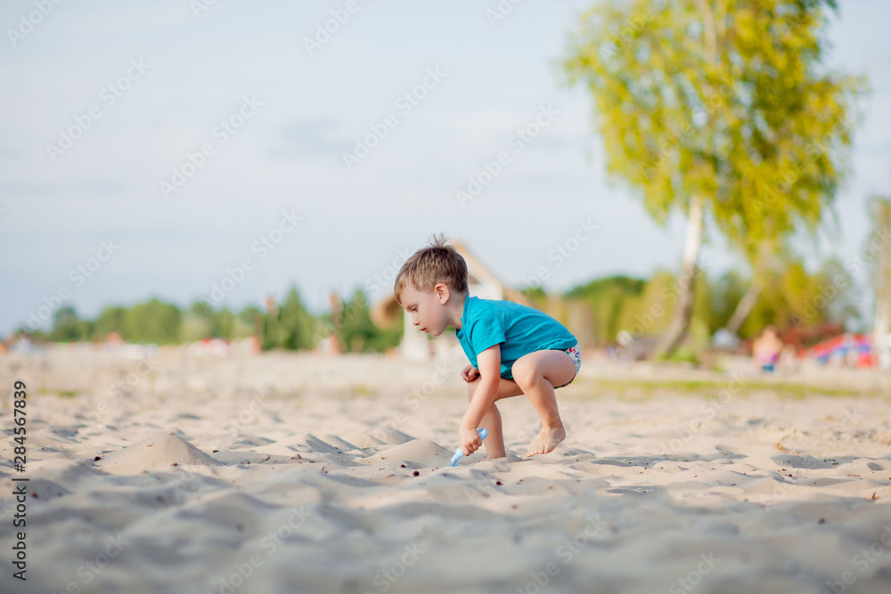 Boy playing on beach. Child play at sea on summer family vacation. Sand and water toys, sun protection for young child. Little boy digging sand, building castle at ocean shore.