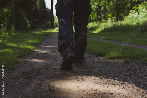 man walking along a forest trail, rear view on legs