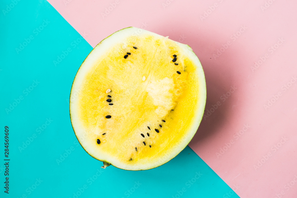 half of ripe yellow watermelon on pink-blue background half of ripe yellow watermelon on pink-blue background