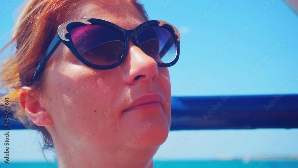 Close up portrait of a woman in sunglasses enjoying the breeze on a background of sea landscape. A woman is enjoying the vacation.1920X1080 Full Hd. Close up portrait of a woman in sunglasses enjoying the breeze on a background of sea landscape. A woman is enjoying the vacation.1920X1080 Full Hd.