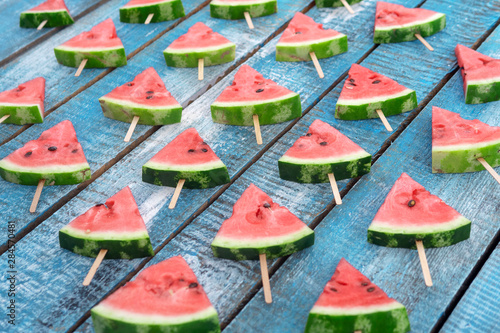 Triangular slices of watermelon on a blue wooden background.