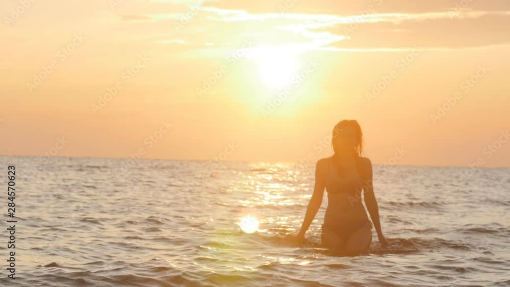 silhouette figure of a woman coming out from the water in a swimsuit at dawn, a girl swimming in the sea enjoying sunrise, the concept of summer vacation and health silhouette figure of a woman coming out from the water in a swimsuit at dawn, a girl swimming in the sea enjoying sunrise, the concept of summer vacation and health