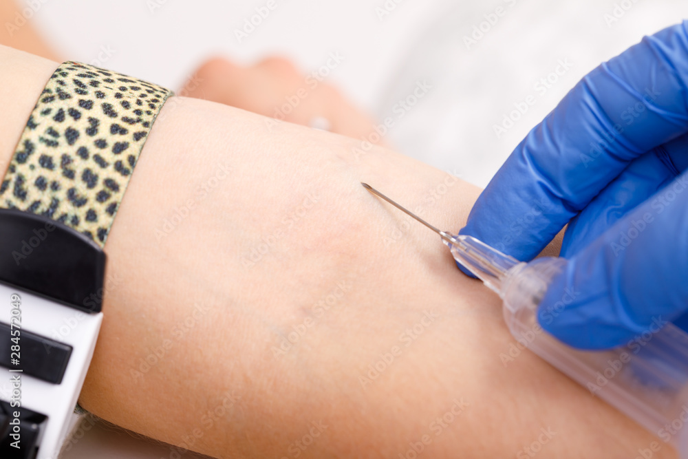 Nurse takes a blood sample from arm vein performing a venipuncture Nurse takes a blood sample from arm vein performing a venipuncture