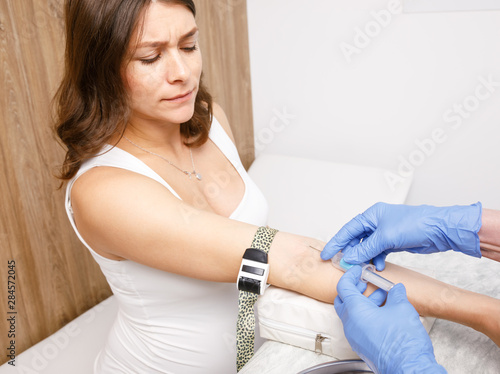 Nurse takes a blood sample from arm vein of pregnant woman performing a venipuncture photo