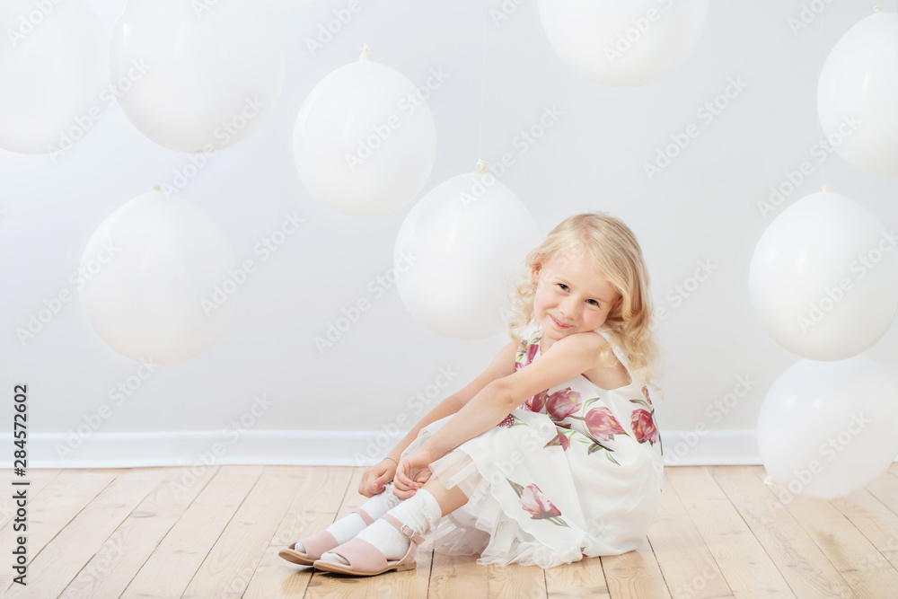 little girl with white balloons indoor
