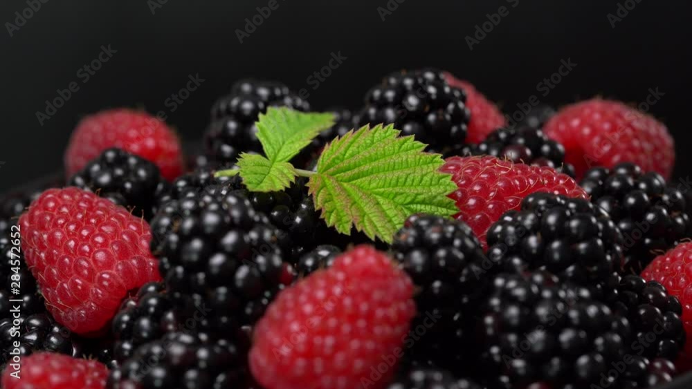 Background from fresh organic blackberries and raspberries. Lot of ripe juicy wild fruit raw berries on a plate rotates. Blackberry and raspberry, close up Background from fresh organic blackberries and raspberries. Lot of ripe juicy wild fruit raw berries on a plate rotates. Blackberry and raspberry, close up