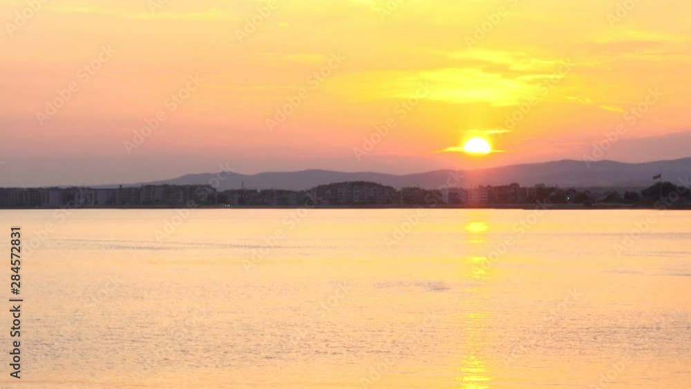 View of the calm sea and the coast in the picturesque colors of sunset