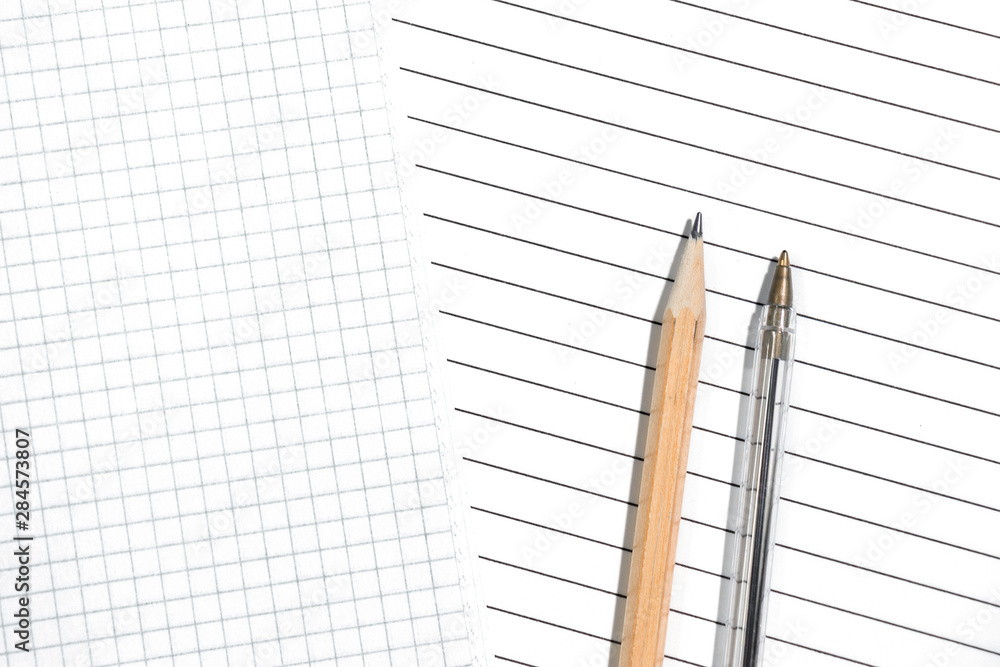 Close-up of checkered and striped sheets with pencil and pen. The choice of the two options. Top view, copyspace Close-up of checkered and striped sheets with pencil and pen. The choice of the two options. Top view, copyspace