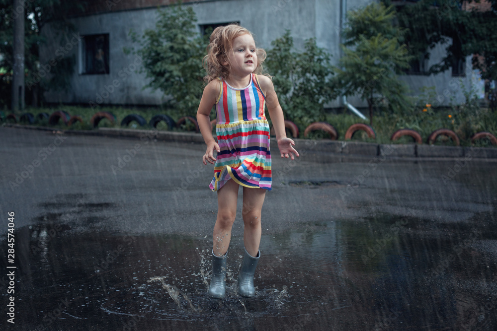 Little girl jumping in the puddles. Little girl jumping in the puddles.