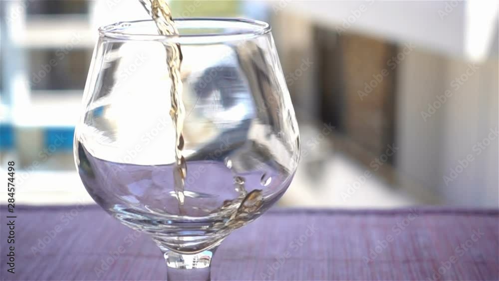 Cognac is poured into an empty glass in slow motion Cognac is poured into an empty glass in slow motion