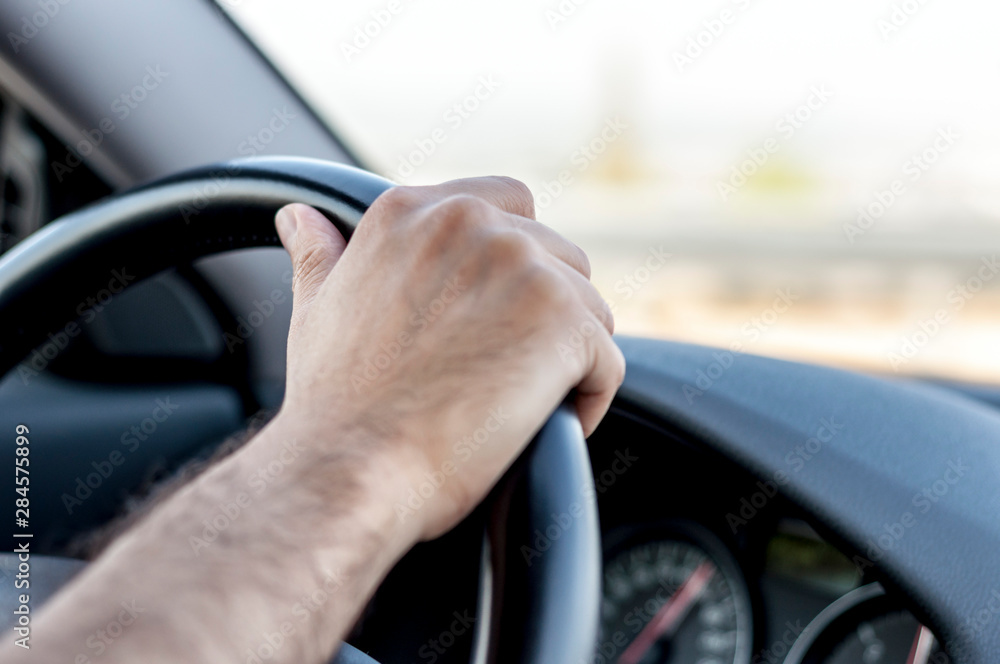 Male hand using a steering wheel