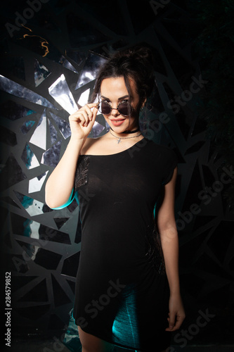 Beautiful goth fashion stylish girl in black round vintage sunglasses on black studio background